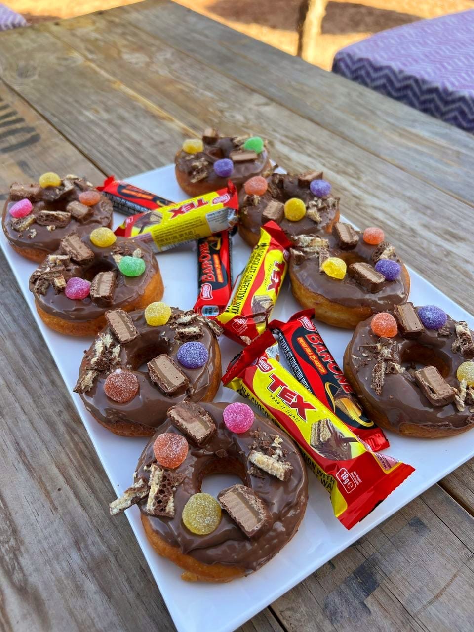 Chocolate-glazed doughnuts topped with sweets and chocolate bars