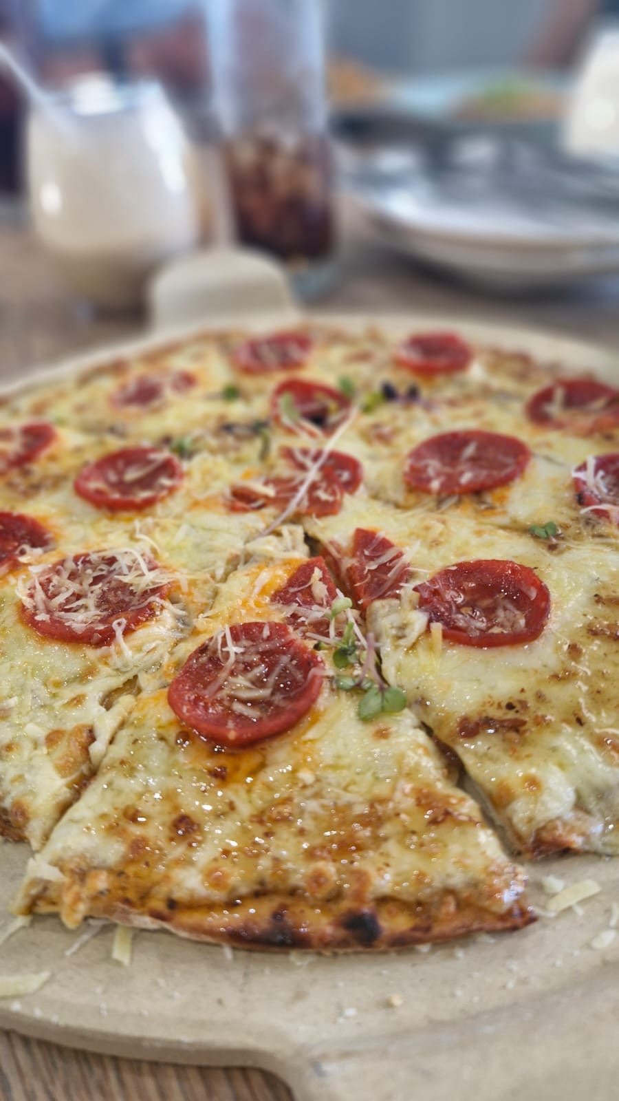 A thin-base pizza with rosa tomatoes, cheese and micro-herbs
