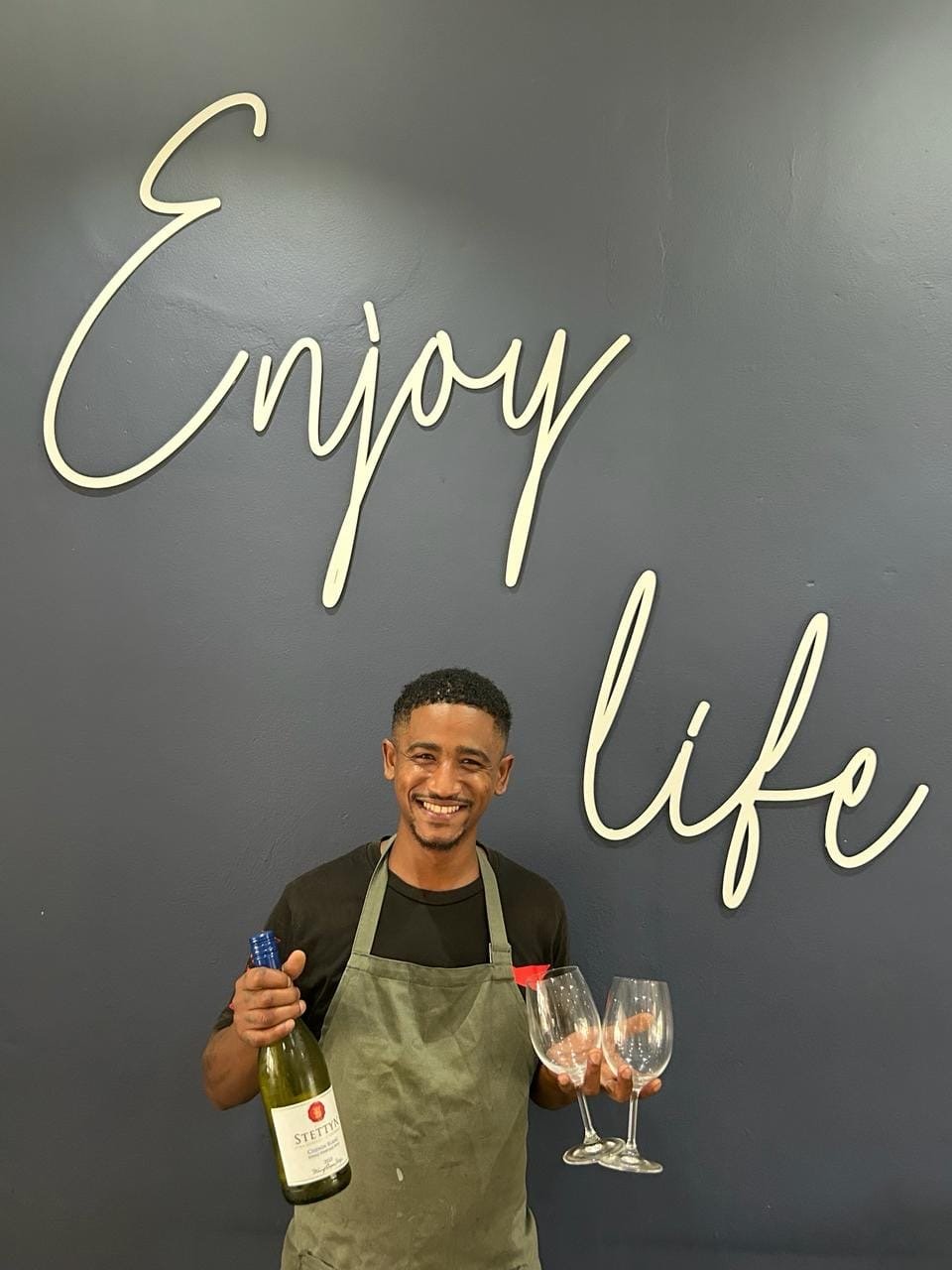 A team member with a bottle of Stettyn and two glasses